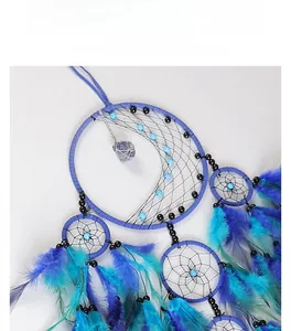 Detail of blue dream catcher featuring hand-woven net with raw stone and gradient feathers