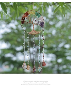 Detail of life tree suncatcher with natural crystal stones hanging on a green tree branch