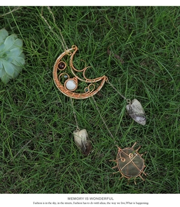 Detail of handmade wire wrapped moon and sun pendants with natural raw amethyst crystals