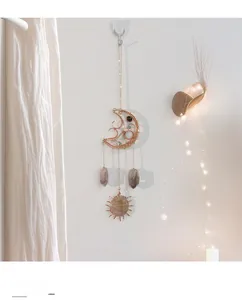 Detail of rose gold moon sun catcher with natural amethyst stones on white wall