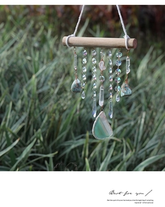 Detail of bohemian crystal wind chime with green agate slice and raw mineral stones