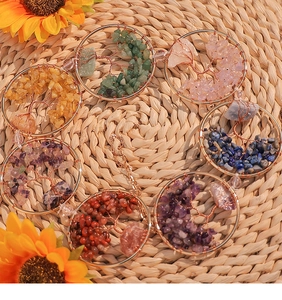 Close-up of handmade Tree of Life wind chimes with colorful tumbled crystals on straw mat