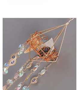 Detail of golden sun catcher with natural crystals and devil eye charms for garden