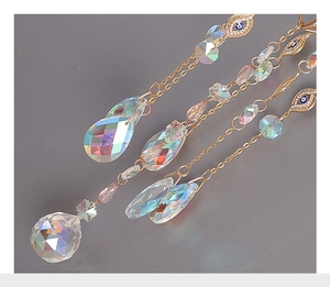 Detailed view of faceted crystal prisms and blue evil eye charms on a golden suncatcher