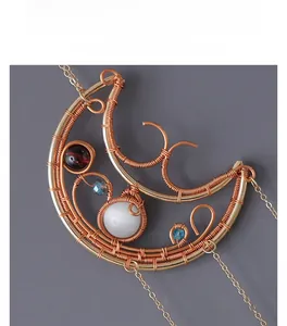 Close-up of handmade crescent moon pendant with colorful beads and gold wire wrapping