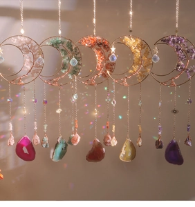 Detail of five moon-shaped suncatchers with natural crystal chips and tree of life design