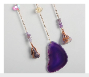Detail of amethyst suncatcher with purple agate slice and golden sun charms on metal chain