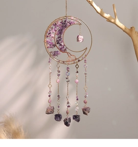 Detail van amethist levensboom in een gouden maan hanger hangend aan een tak