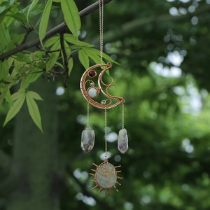 Handmade moon-shaped dream catcher with natural amethyst crystals hanging from a tree branch