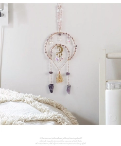Detail of amethyst suncatcher with gold moon charms and hanging crystal prisms on a white wall