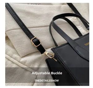 Macro shot of adjustable leather strap with gold buckle and fashion text on black tote