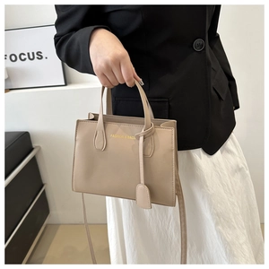Chic beige crossbody bag with top handles shown on model in minimalist interior