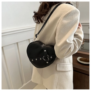 Detail van een zwarte hartvormige leren crossbodytas met zilveren studs en gesp