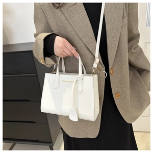 Detail of white leather handbag showing gold FASHION & BAGS print and detachable strap