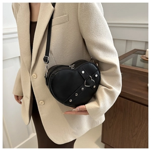 Détail d'un sac cœur avec rivets argentés et boucle sur cuir noir en bandoulière