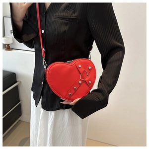Détail du sac bandoulière coeur rouge avec rivets argentés et fermoir en forme de coeur