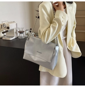 Details der silbernen Ketten-Schultertasche mit Metallic-Finish im schicken Café-Ambiente