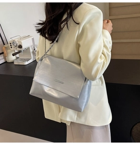 Detailansicht einer silbernen Metallic-Umhängetasche mit Kette am Modell
