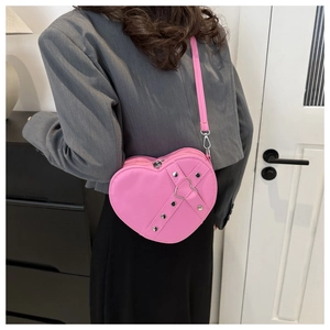 Detail van roze hartvormige tas met zilveren klinknagels en metalen ringen decoratie