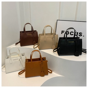 Five minimalist square handbags in brown, beige, black, and white on a display stand
