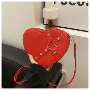 Détail du sac à main rouge en forme de cœur avec rivets et sangles croisées