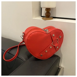 Detail van rode hartvormige crossbodytas van PU-leer met metalen klinknagels en riem