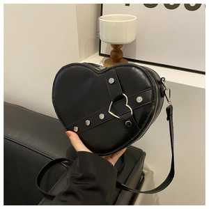 Détail du sac à bandoulière noir en forme de cœur avec rivets et anneau en métal