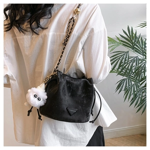 Detail van zwarte bucket bag met trekkoord, kettingriem en wit schaapvormig hangertje