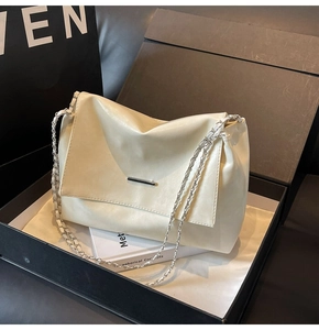 Nahaufnahme der beigen Lederumhängetasche mit silberner Kette in einer Geschenkbox