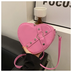 Détail d'un sac cœur rose avec des clous argentés et une boucle métallique en forme de cœur