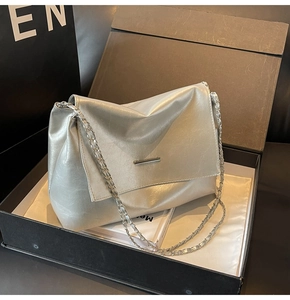 Detail einer silbernen Umhängetasche mit Kettenriemen in einer schwarzen Geschenkbox