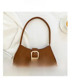 Detail view of brown vintage baguette bag with golden D-ring buckle on white fabric