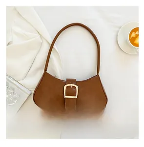 Brown vintage underarm bag with gold buckle on white fabric next to coffee