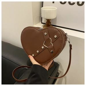 Détail du sac à bandoulière marron en forme de cœur avec clous argentés et boucle métal