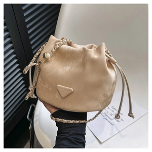 Detail van beige emmertas met trekkoord, gouden ketting en verstelbare gouden bal