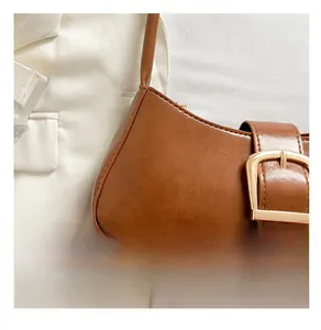 Detailed macro view of caramel brown vintage baguette bag with large gold buckle