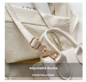 Detail of adjustable strap buckle and gold metal hardware on a white leather handbag