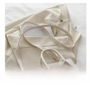 Detail view of the slim cream leather shoulder strap with elegant gold metal buckles