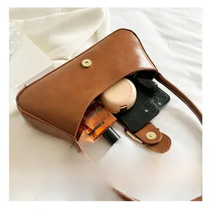 Interior capacity of vintage brown leather bag showing phone and cosmetics