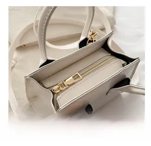 Detailed top view of the smooth golden metal zipper on the white leather handbag