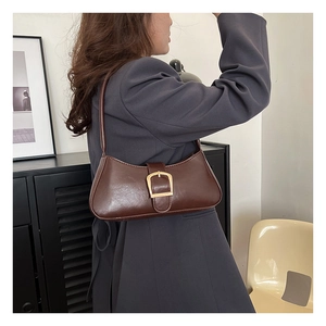 Detail view of deep brown faux leather baguette bag with a gold square buckle