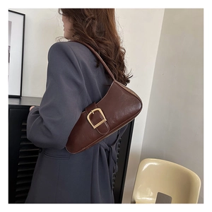 Close-up of a vintage dark brown leather baguette bag with a large gold metal buckle