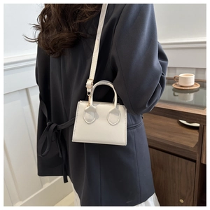 Detailed view of a white minimalist square handbag with smooth leather and gold hardware