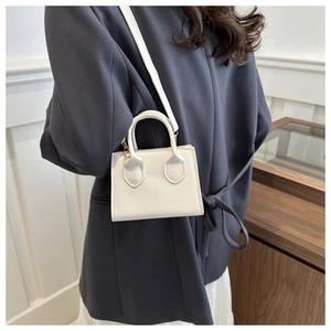 Rear view of a white minimalist square handbag with top handle and shoulder strap detail