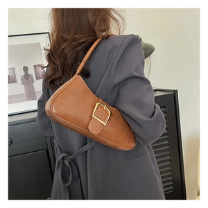 Brown vintage underarm bag with gold metal buckle shown on model in a modern room