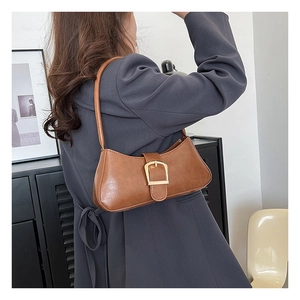 Detail of vintage brown shoulder bag with textured faux leather and gold square buckle