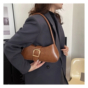 Detail of dark brown baguette bag featuring a textured leather finish and large gold buckle