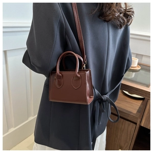 Deep brown crossbody bag with smooth texture shown in a modern home interior setting
