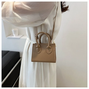 Chic khaki mini handbag styled with a white dress, showing crossbody strap and handle details