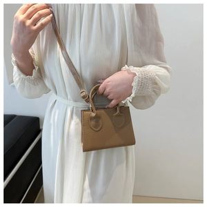 Mini khaki square shoulder bag shown on model with adjustable strap and vintage stitching